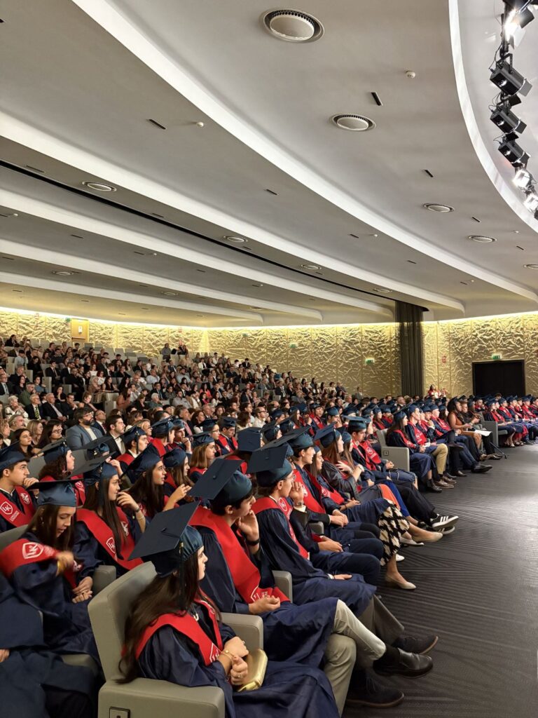 Studenti con toga e tocco seduti in auditorium durante la cerimonia di graduation del doppio diploma americano.
