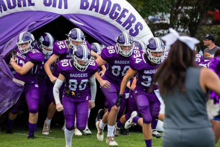 Giocatori di football americano entrano in campo dal tunnel gonfiabile della squadra.