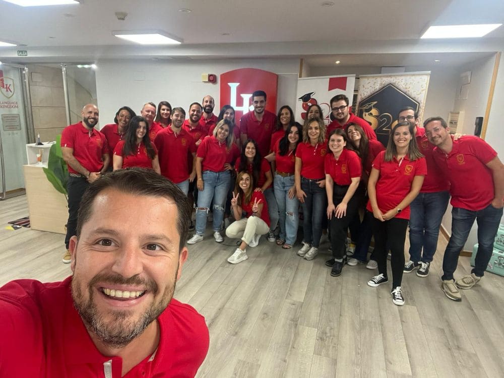 Selfie di gruppo del team di LK in maglietta rossa, negli uffici della scuola.