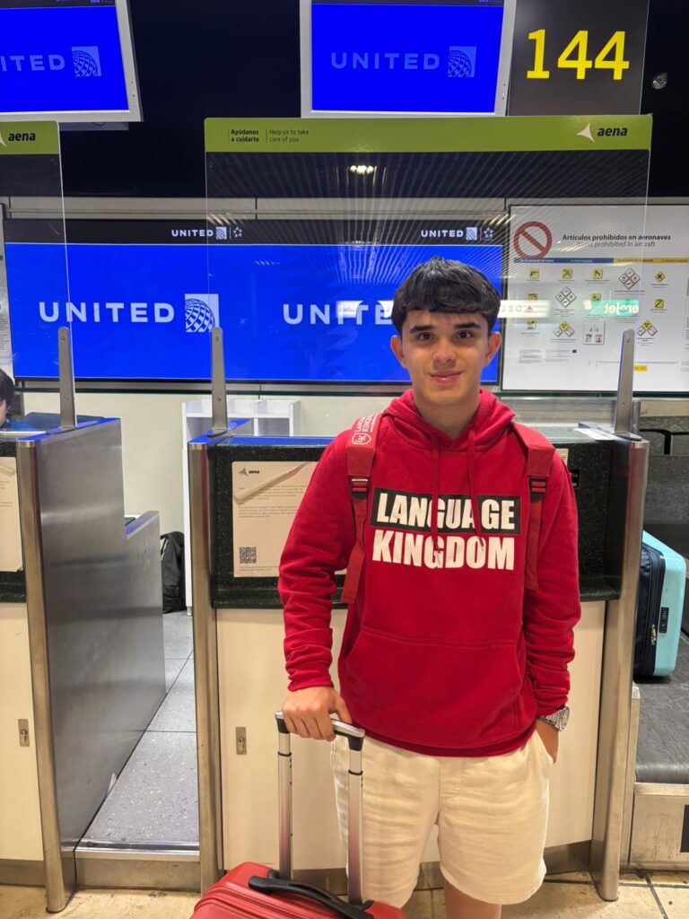 Studente con la felpa di Language Kingdom al banco del check-in in aeroporto.