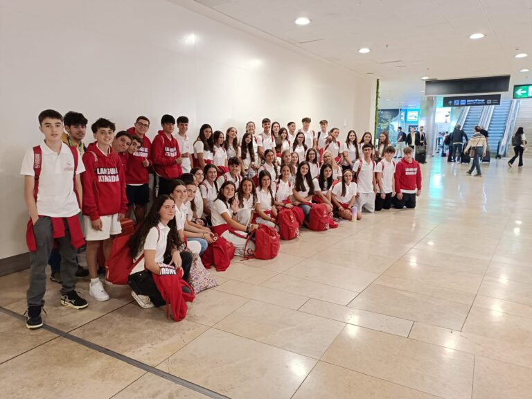 Gruppo molto numeroso di studenti con le borse rosse LK nel terminal dell'aeroporto.