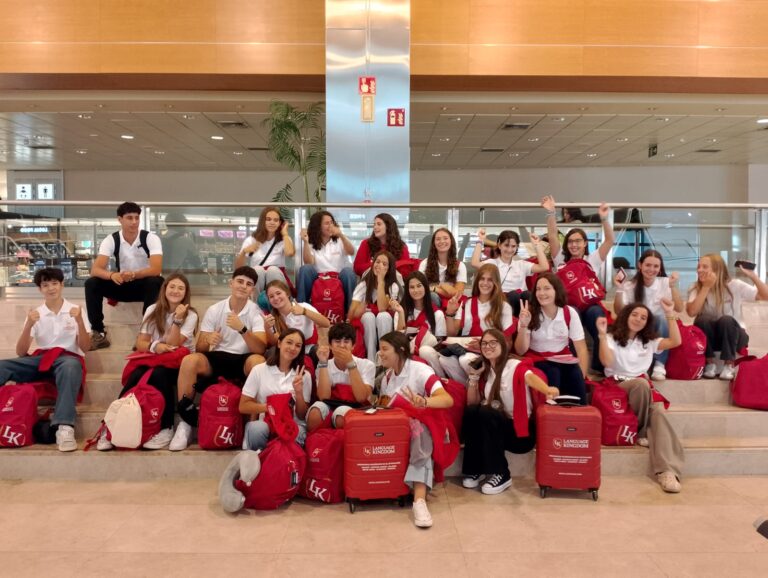 Studenti seduti sulle valigie rosse di Language Kingdom in aeroporto.