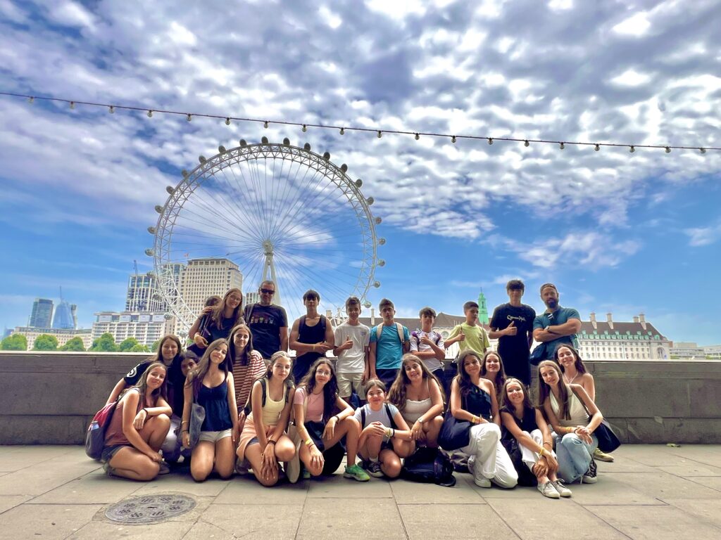 Gruppo numeroso di studenti davanti al London Eye, sul lungofiume del Tamigi.