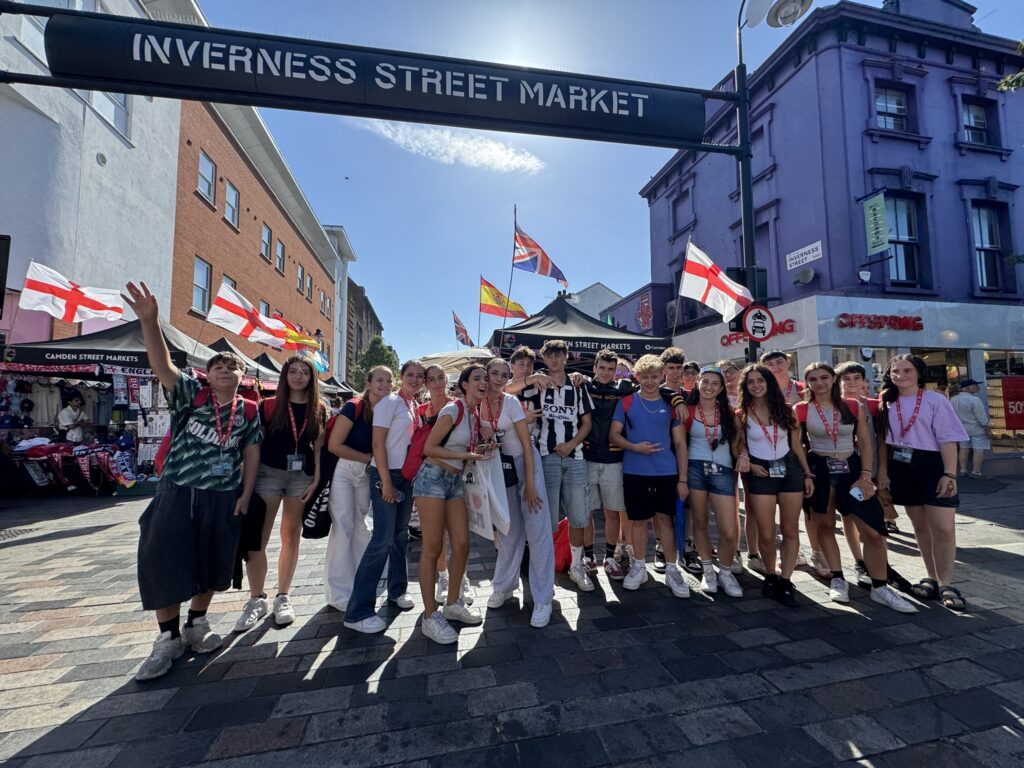 Gruppo di studenti sotto l'insegna dell'Inverness Street Market, a Camden.