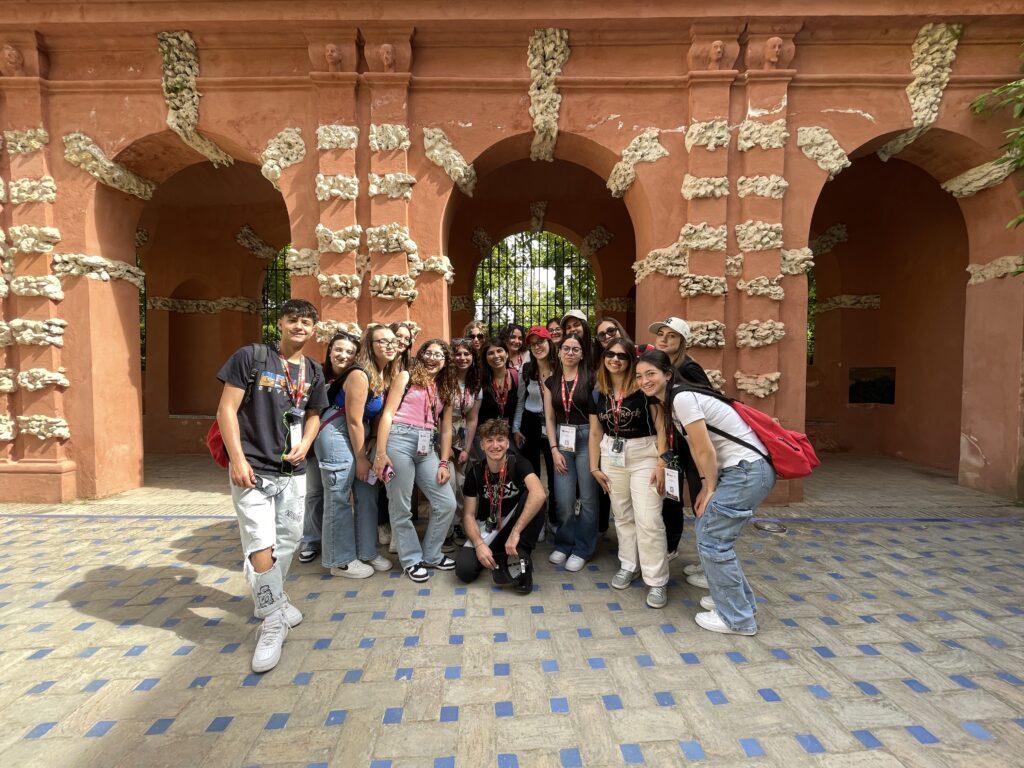 Gruppo di studenti sotto un arco in mattoni rossi, a Siviglia.