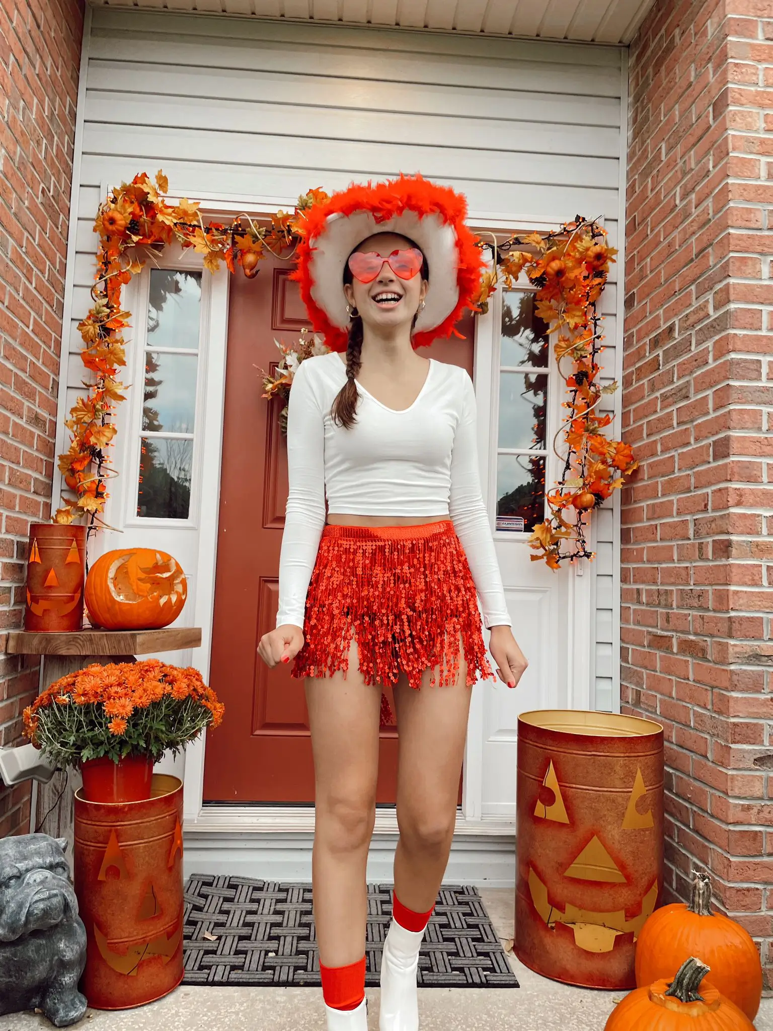 Studentessa internazionale festeggia Halloween in America davanti a una casa decorata con zucche e foglie autunnali.